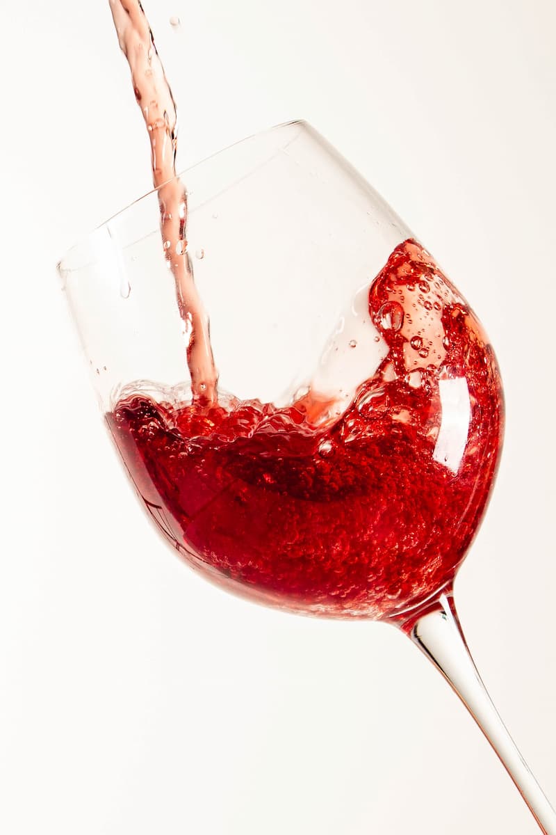Vinho tipo licoroso está sendo derramado em uma taça transparente.