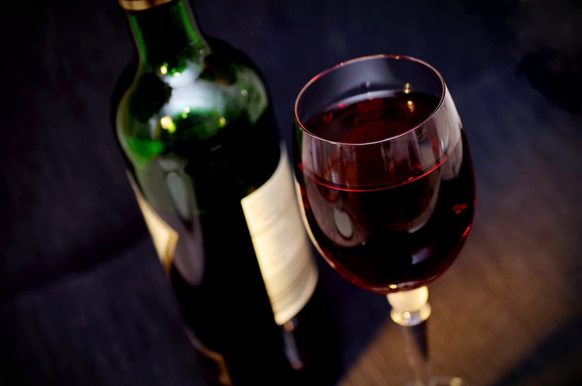 Uma garrafa de vinho com uma taça ao lado, cheia de vinho 
