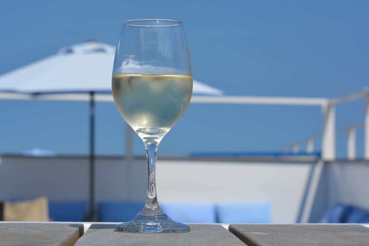 Uma taça de vinho com um fundo de piscina e guarda sol