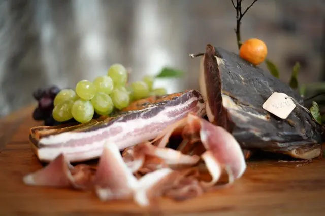 Guanciale inteiro e em fatias sobre tábua de madeira, carne curada utilizada no preparo da carbonara tradicional.