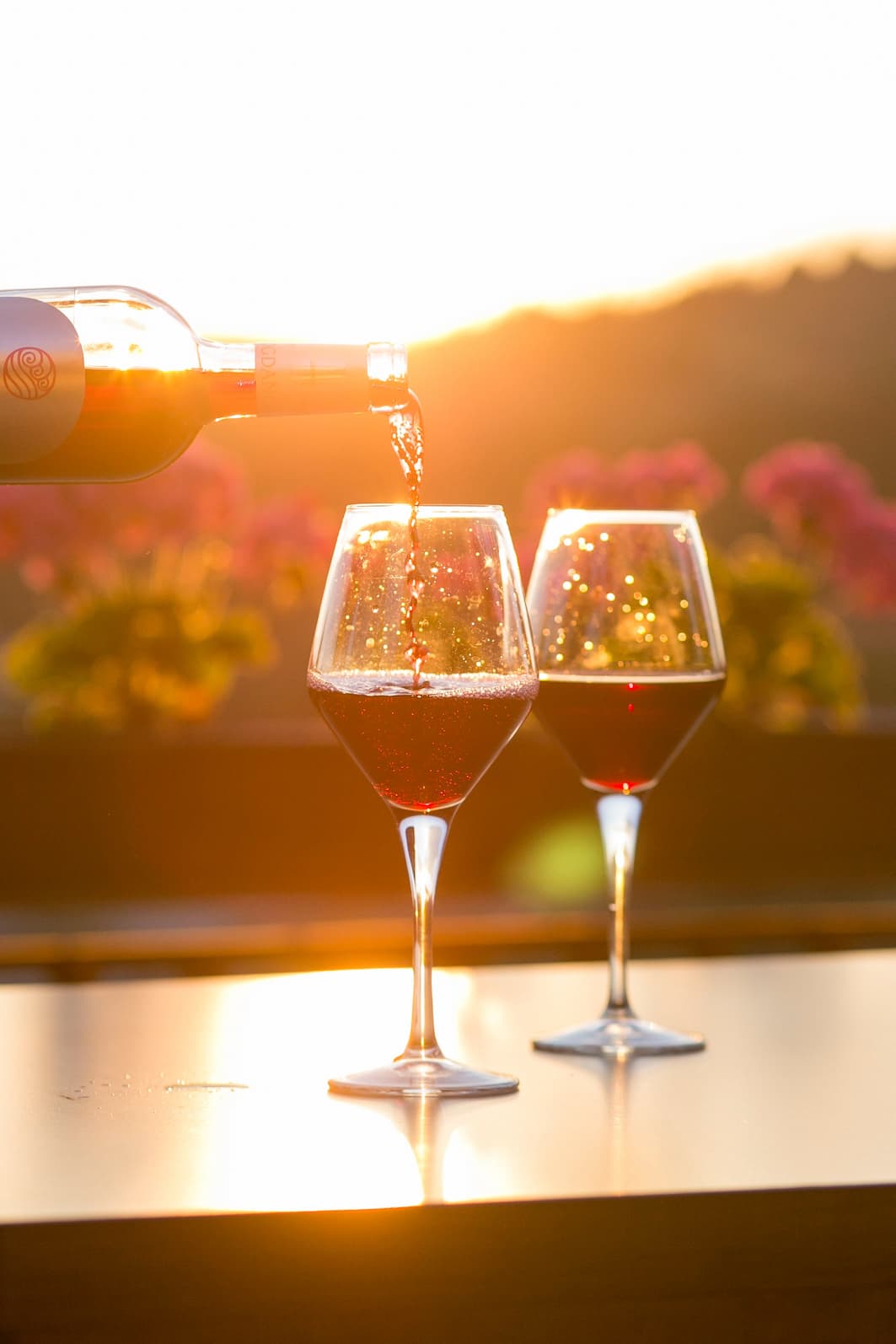 Uma pessoa serve vinho em duas taças de cristal. Imagem disponível em Unsplash.