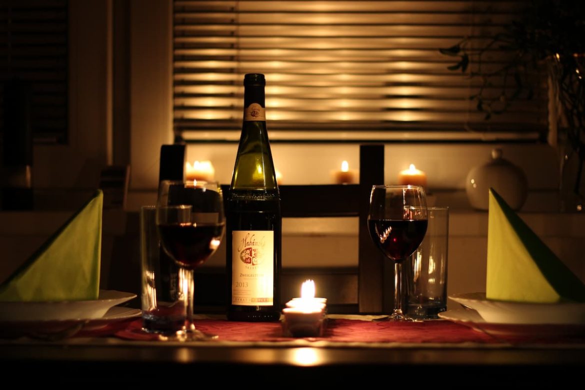 Mesa de centro com vinho, taças e vela. Em uma clima romântico para o dia dos namorados.
