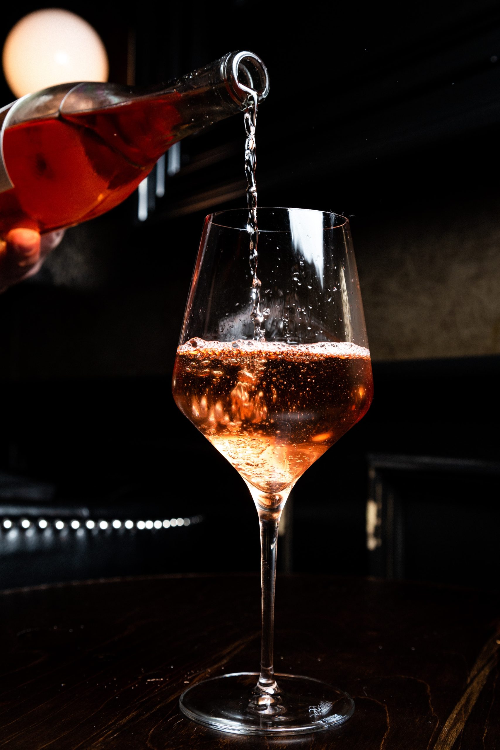 Uma pessoa serve vinho rosé em uma taça.