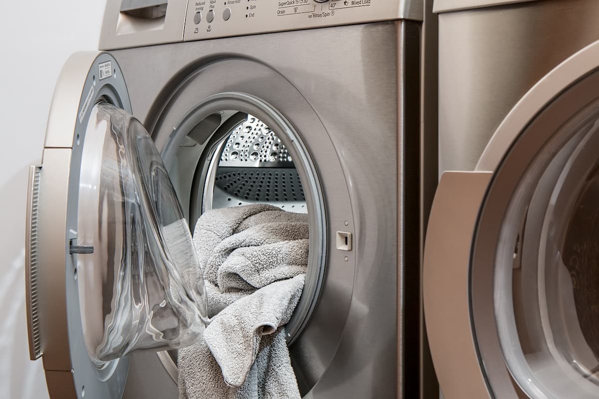 Máquina de lavar inox com tampa aberta e uma tolha branca.