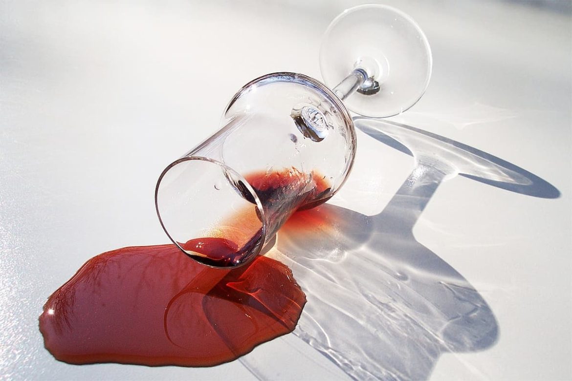 Taça de vinho caída mancha a superfície branca.