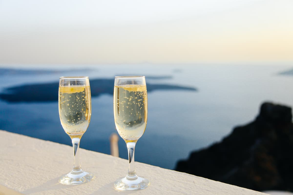 Duas taças de champanhe. Ao fundo há uma paisagem com o mar e algumas ilhas.