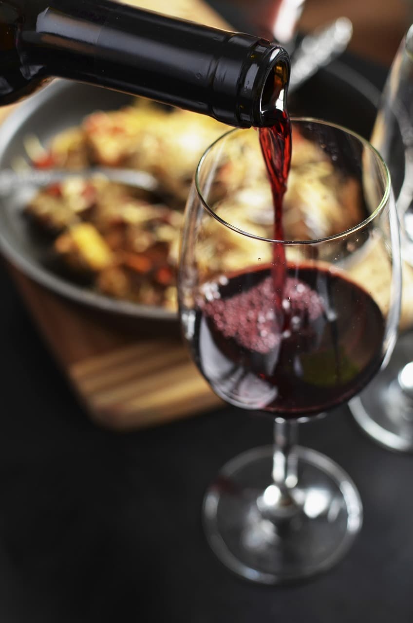 Taça de vinho tinto ao lado de um prato de risoto.