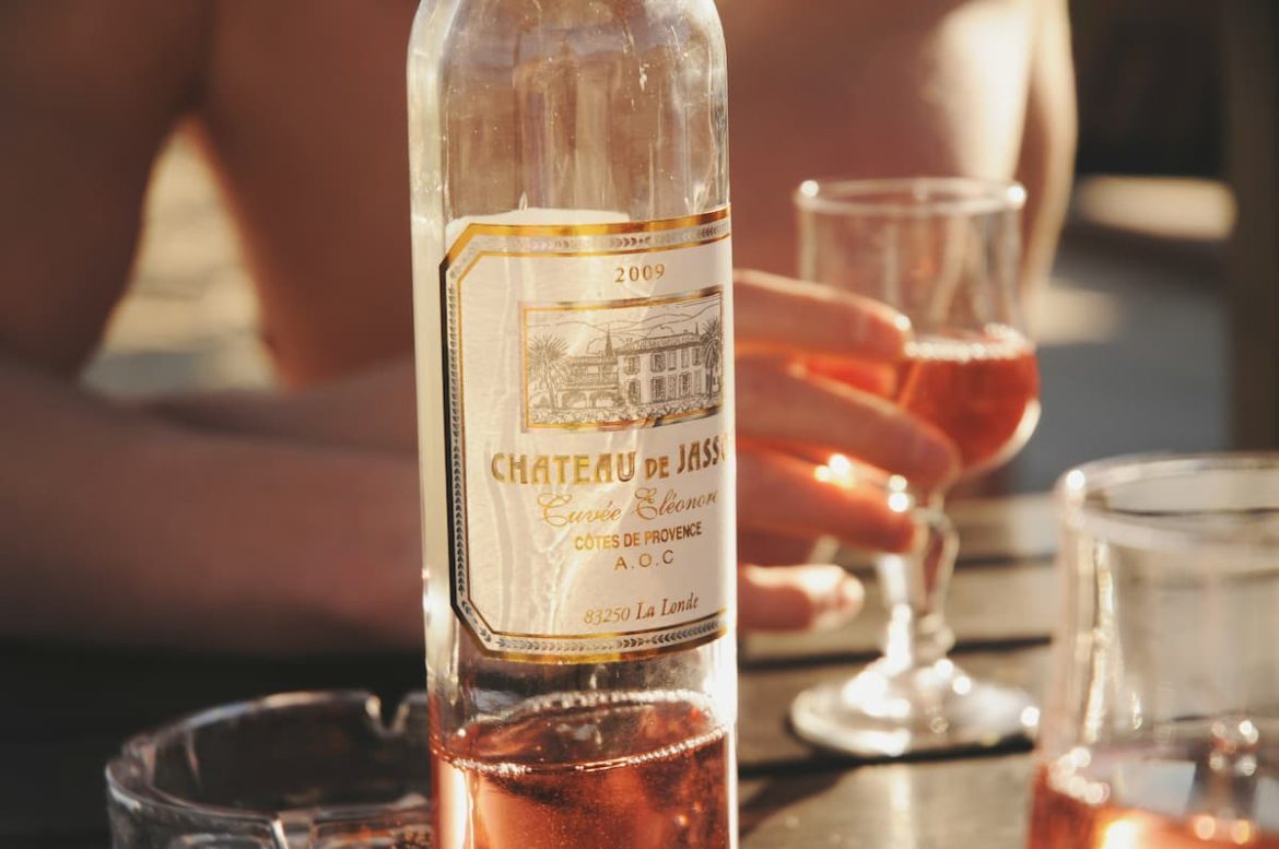 Uma garrafa de vinho rose, com uma taça ao lado