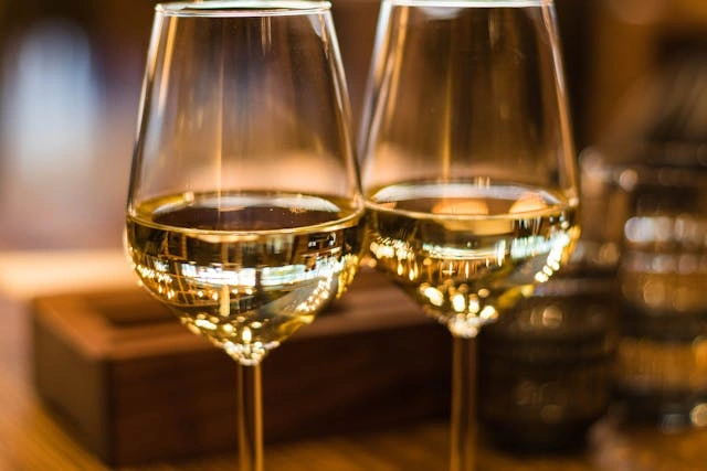 Imagem de duas taças de vinho branco.