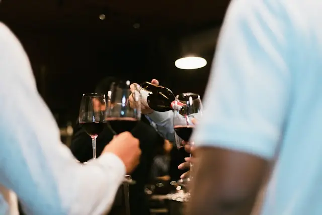 Taças de vinho sendo servidas durante um encontro em ambiente interno.