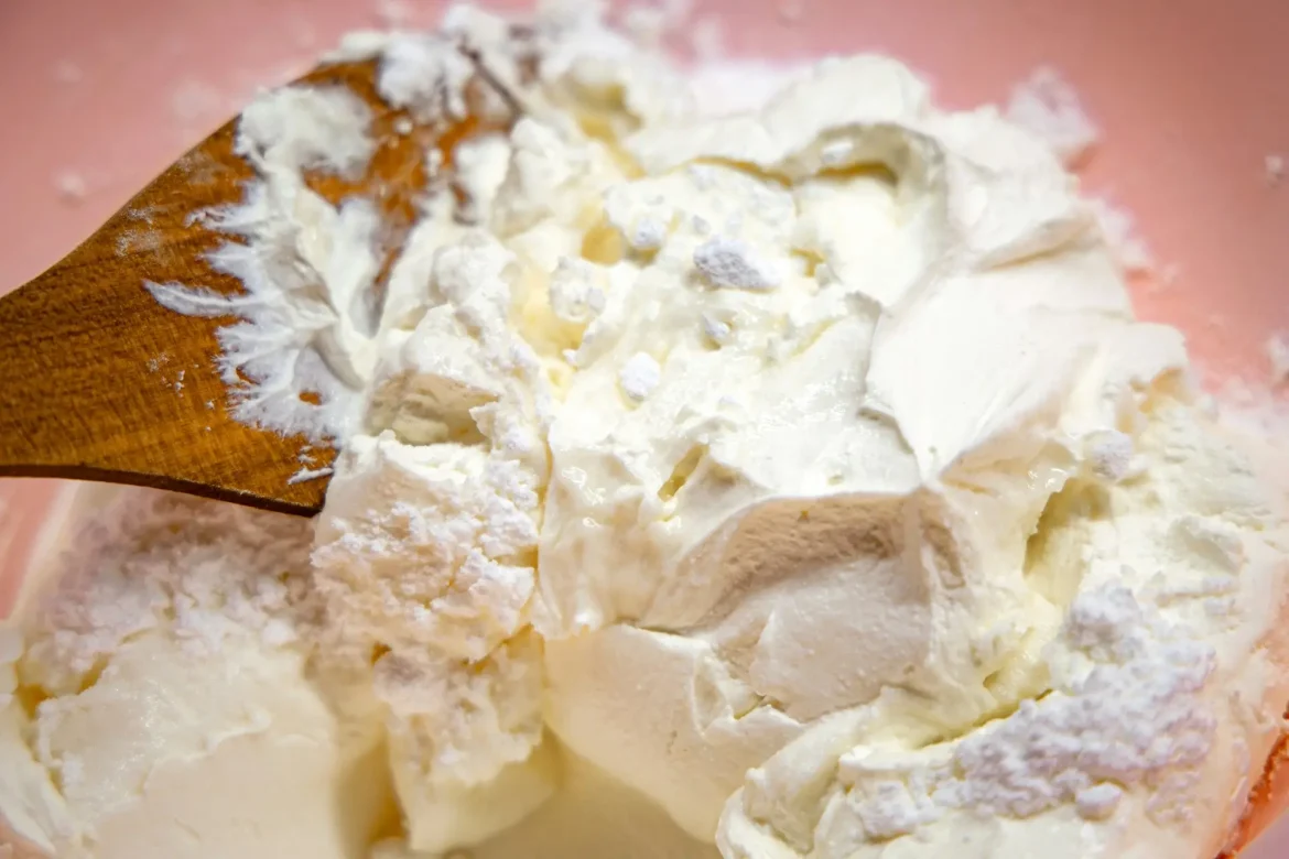 Queijo mascarpone cremoso sendo servido com colher de madeira.
